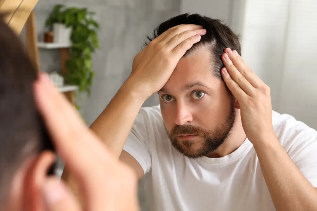 man with hair loss problem looking at mirror indoo utc