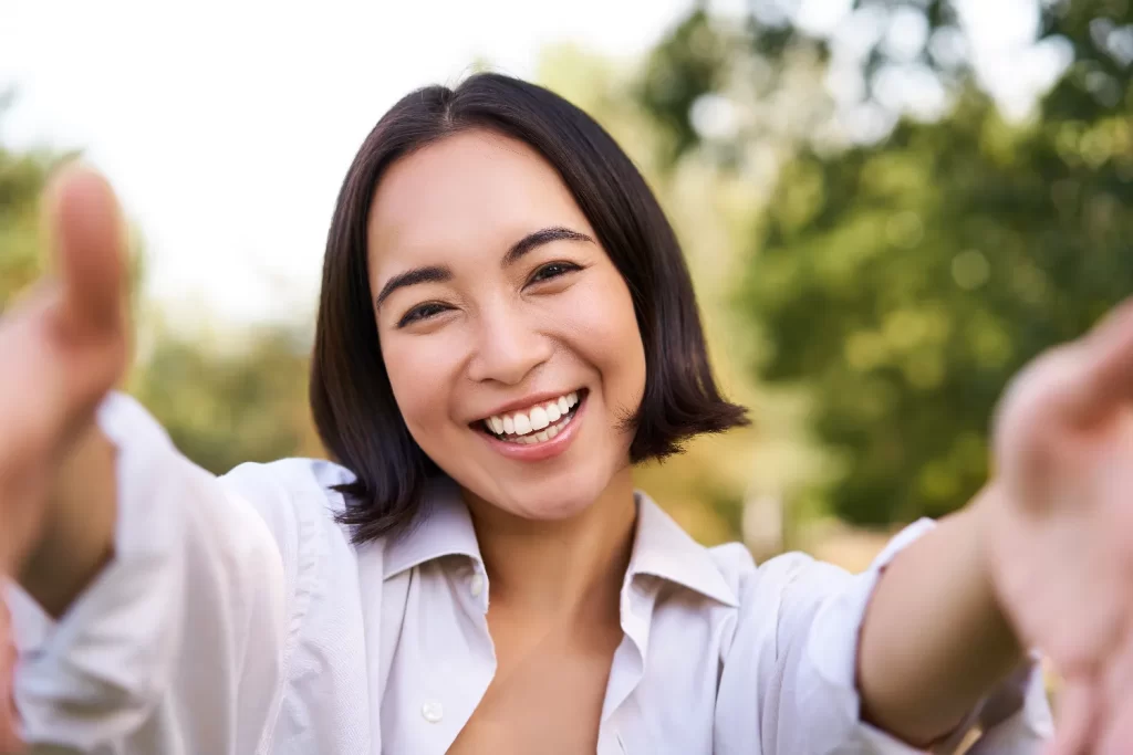 smiling asian girl takes selfie video chats hold utc